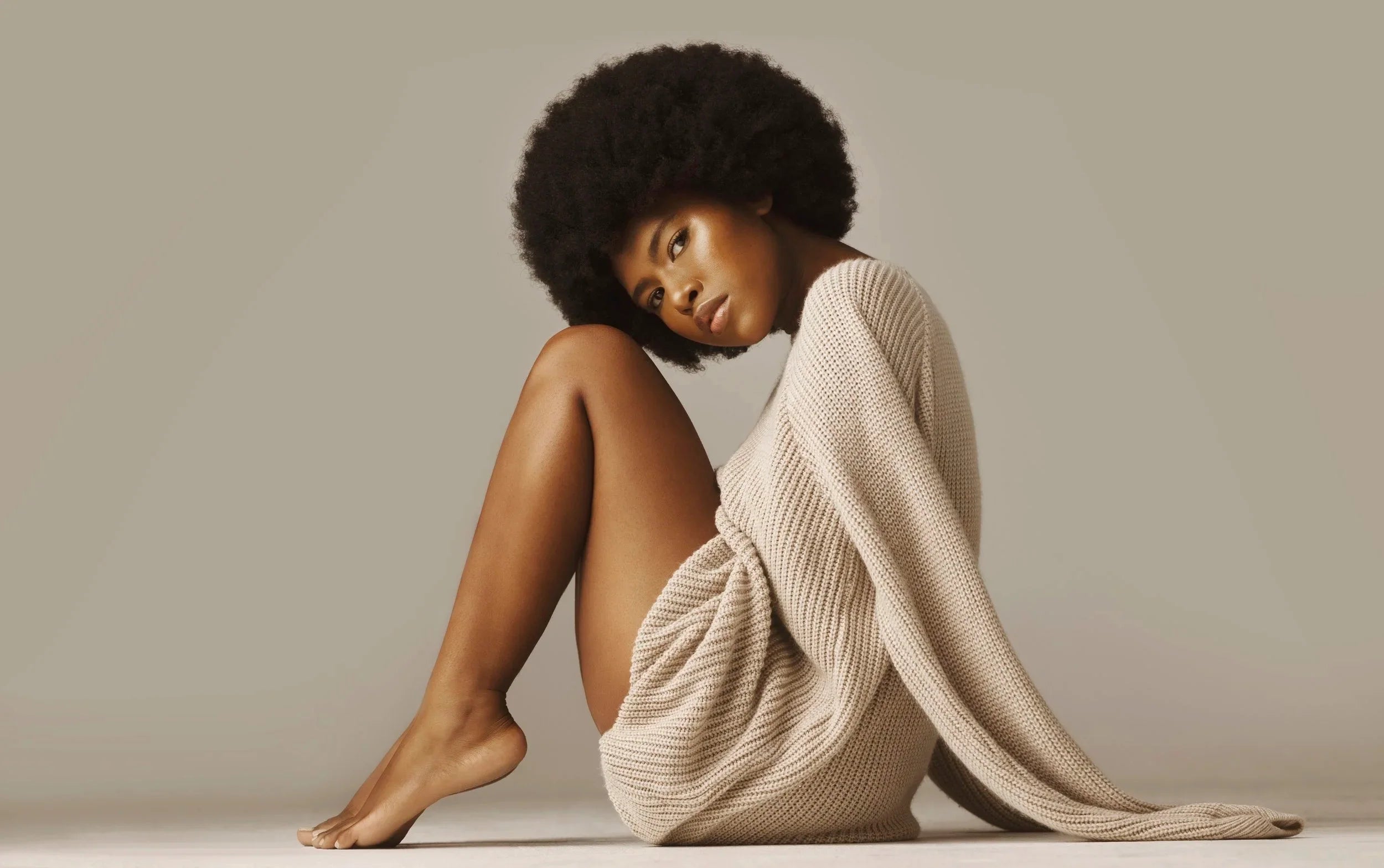 Modle with healthy, hydrated coils representing hair care products and natural hair treatments.
